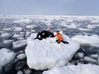 Zwei Menschen liegen im Trockenanzug auf einer Eisscholle