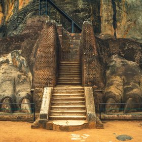 Zwei riesige Löwentatzen aus Stein umrahmen den Treppeneingang der Felsenfestung