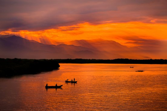 Boote auf dem Meer bei einem traumhaft roten Sonnenuntergang in Kolumbien bei Santa Marta