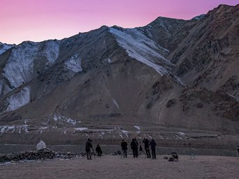 Menschen stehen auf Bergplatasu im Sonnenuntergang