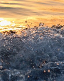 Welle bricht an Strand bei Sonnenuntergang