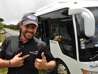 Reiseleiter Jonathan Serrano glücklich vor einem Reisebus