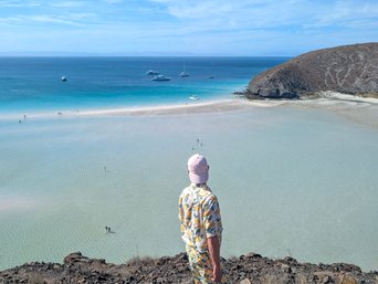 Ein Mann schaut sich von einer anhöhe aus das türkisene Wasser des Playa Balandras an