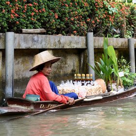 Eine Gemüsehändlerin sitzt in ihrem Boot am Flussufer