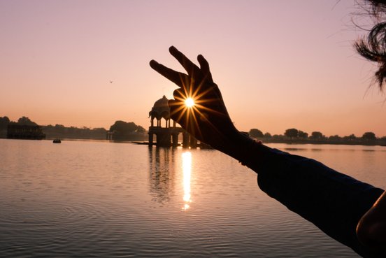 Finger umschließen optisch die Sonne