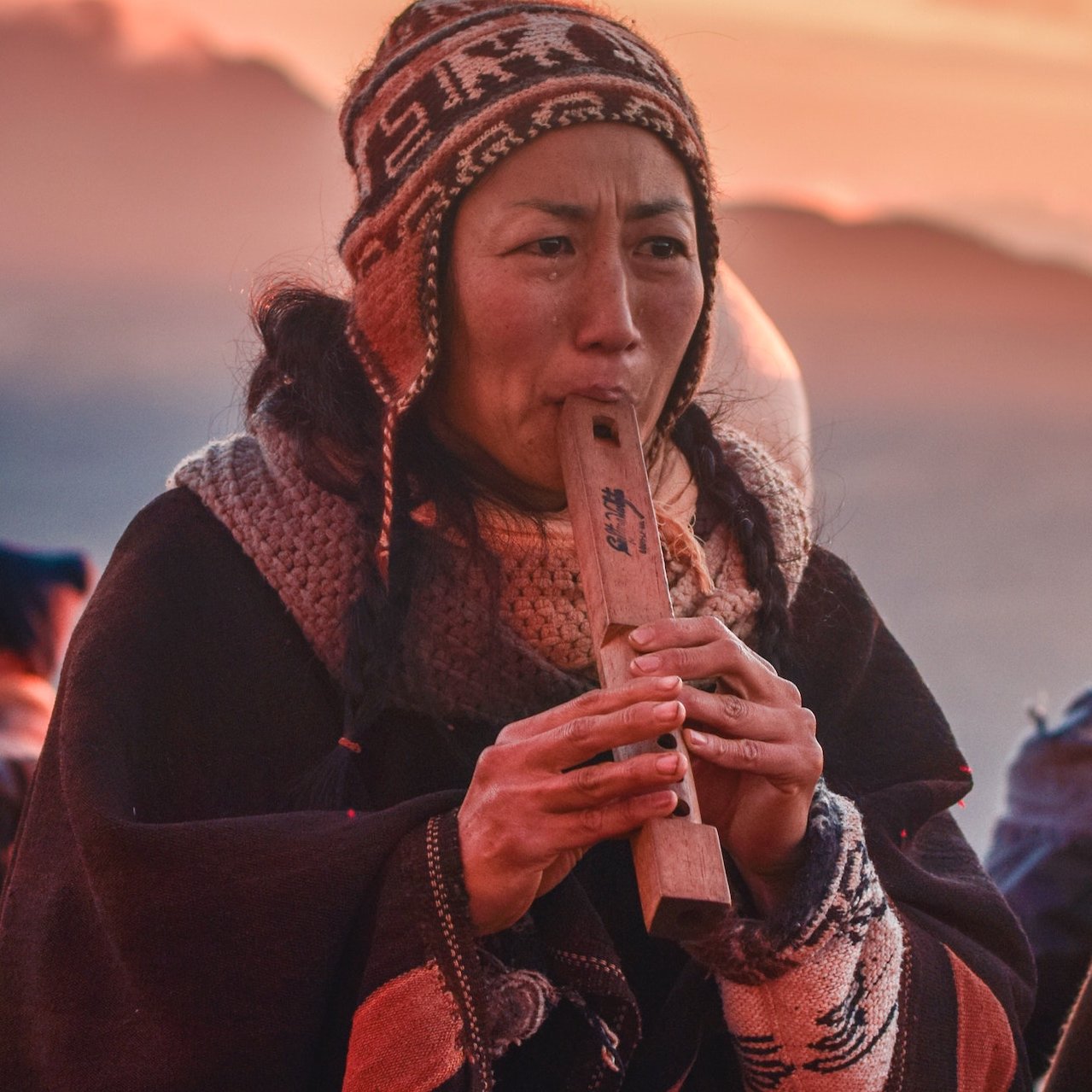 Frau im Sonnenuntergang spielt eine Art Flöte