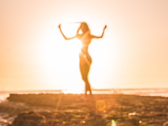 Verschommenes Bild einer Frau im Sonnenuntergang am Strand