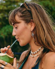 Frau trink am Strand aus einer Kokosnuss