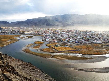 mongolei rundreise 2 wochen fluss mit stadt im hintergrund und bergen 
