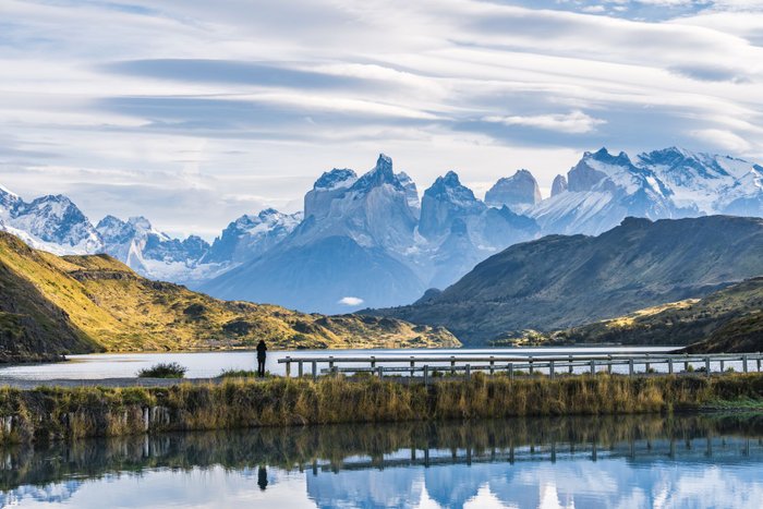 Person steht am Ufer eines Sees mit Bergkette im Hintergrund - Chile Nationalparks