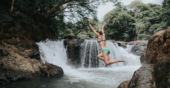 Costa Rica Natur und Abenteuer - eine Frau springt ins Wasser bei einem Wasserfall