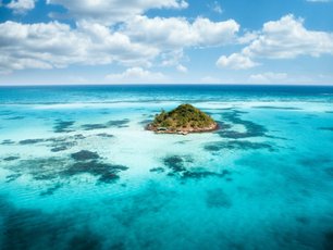 Eine kleine Insel in der Karibik umgeben von kristallklaren Wasser.