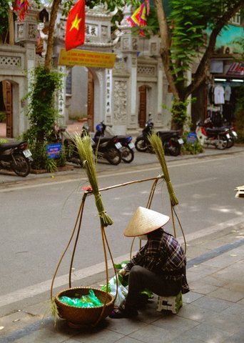Mann mit Strohhut und Körben in Straße