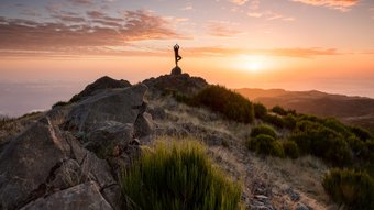 Mensch macht Yoga bei Sonnenaufgang auf einem Berg