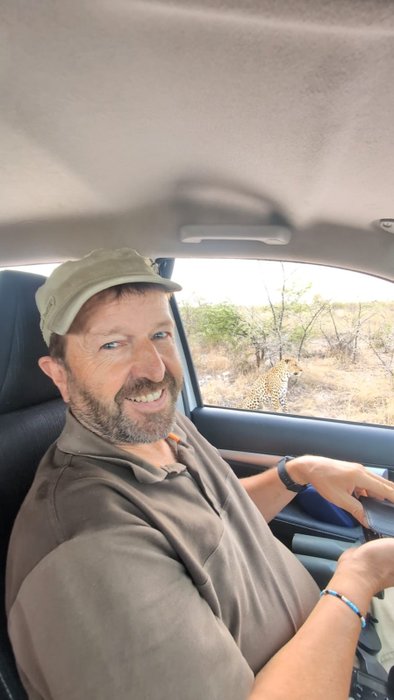 Rainer Stoll in Botswana. Leopard sitzt vor dem Auto.