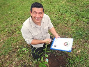 Adolfo pflanzt in La Tigra einen Baum und zeigt das Zertifikat dazu.
