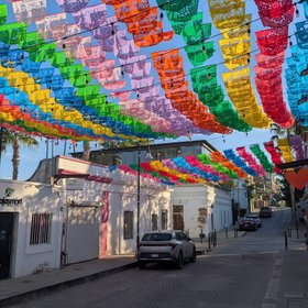 Bunte Fahnen zieren den blauen Himmel einer Straße der Altstadt San Joses in Baja California