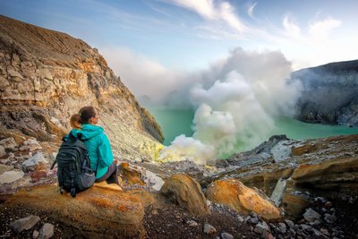 Frau schaut auf einen dampfenden Vulkan in Indonesien