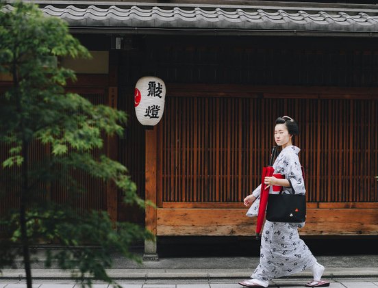 Japanisches Geisha läuft an Haus vorbei
