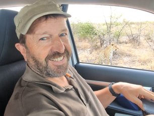 Rainer Stoll in Botswana. Leopard sitzt vor dem Auto.