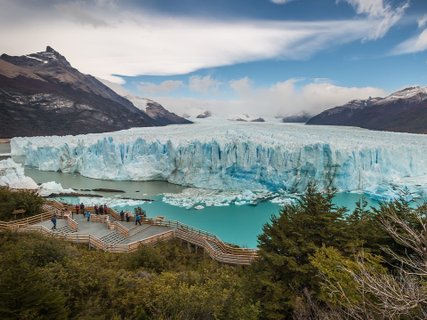 Patagonien Rundreise Selbstfahrer - Perito Moreno Gletscher - Gletscherfront mit türkisfarbenem Wasser, umgeben von Bergen und einem Holzsteg mit mehreren Menschen