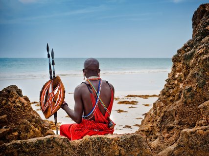 ????????????????????????????????????????????????????????????????????????????????????????????????????????????????????????????????? African man of the Maasai tribe in Kenya sits on the ocean and looks into the distance. The flavor of the journey. Travel Cul