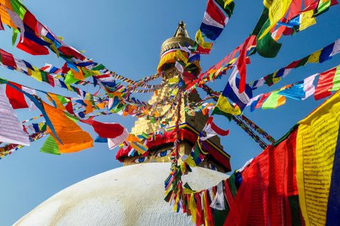 The Bouddhanath Temple in Kathmandu, Nepal. The temple has many colourful prayer flags with ’om mani padme hum’ mantra written on them attached to it’s golden rooftop. Spirituality and meditation.