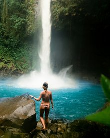 Frau steht am Wasserfall in La Fortuna