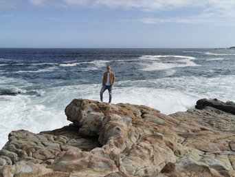 Ein Mann steht auf einem Felsen am Meer