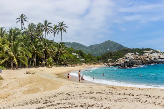 Menschen am Strand von Tayrona. Türkisblaues Wasser und Palmen. 