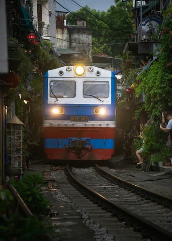 Zug fährt durch enge Gasse mit Häusern