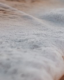Gischt einer Welle am Sandstrand