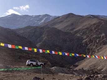 Auto steht am Beghang, davor Gebetsfahnen
