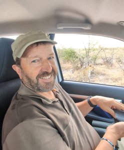 Rainer Stoll in Botswana. Leopard sitzt vor dem Auto.