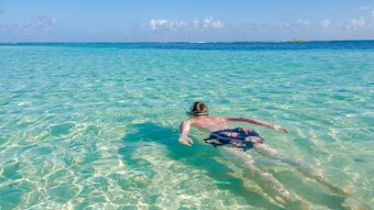 Mann schwimmt im türkisfarbenen Wasser
