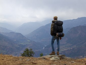 Junger Mann von hinten wie er in ein Tal schaut