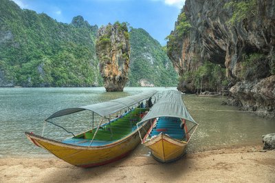 Zwei Boote liegen im Wasser am Ufer vor hohen Karstfelsen