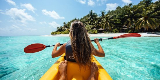 Zwei Menschen im einem gelben Kayak in türkisfarbenen Wasser