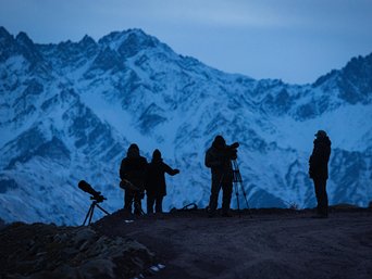 Menschen stehen vor Bergkulisse im Dunkeln