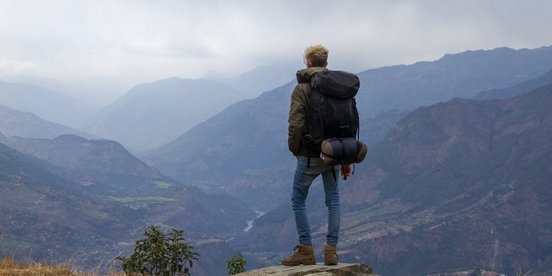 Junger Mann von hinten wie er in ein Tal schaut
