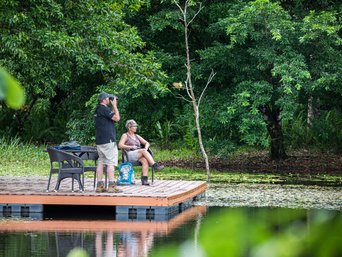 Zwei Personen sitzen auf einer Holzterrasse am Wasser