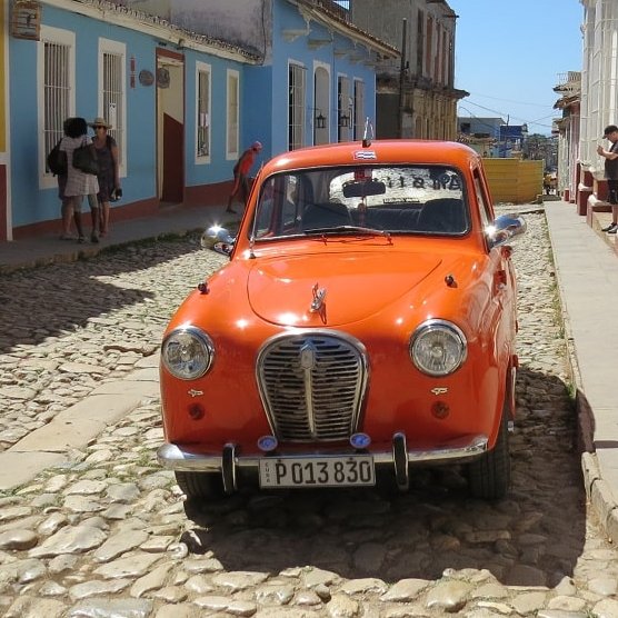 Orangener Oldtimer in einer Straße in Kuba