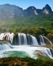 Terrassenförmiger Wasserfall mit Karstbergen im Hintergrund