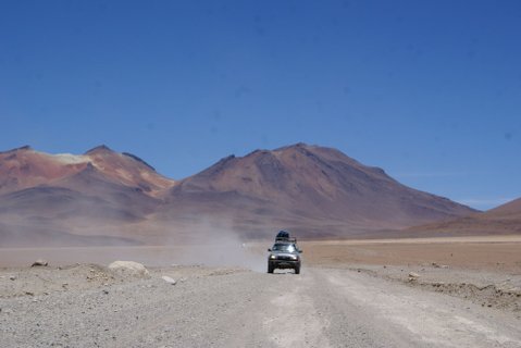 Peru & Bolivien Rundreise - Fahrzeug auf Schotterstraße mit Bergen im Hintergrund