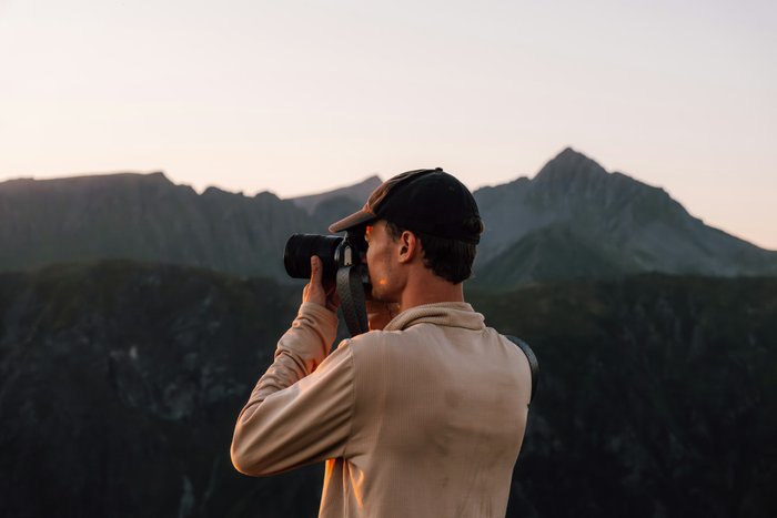 Mann fotografiert das Bergpanorama bei Sonnenuntergang
