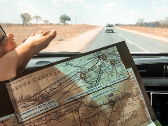 Frau mit Füßen auf dem Armaturenbrett schaut auf einer Karte beim Autofahren