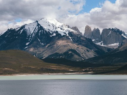 Patagonien Rundreise Selbstfahrer - Torres del Paine - Berglandschaft mit schneebedeckten Gipfeln, bewölktem Himmel und See im Vordergrund
