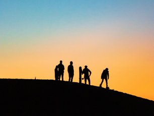 Menschen beim Sandboarding während Sonnenuntergang