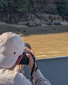 Brasilien pantanal fotoreise - mann von hinten man sieht kopf und hand in kamera - vor ihm ein fluss mit jaguarn dahinter
