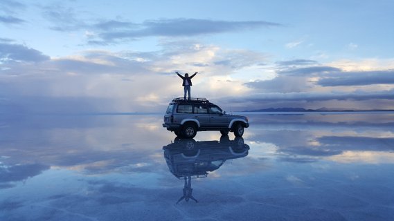 Bolivien Rundreise - Auto auf spiegelndem Wasser im Salar de Uyuni